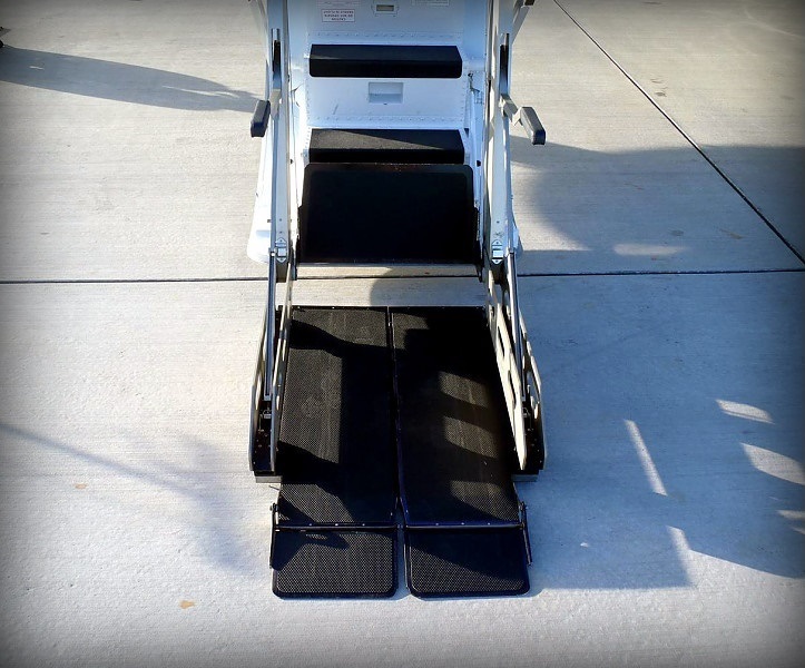 Wheelchair lift ramp lowered to the tarmac beside a private jet in Naples, Florida